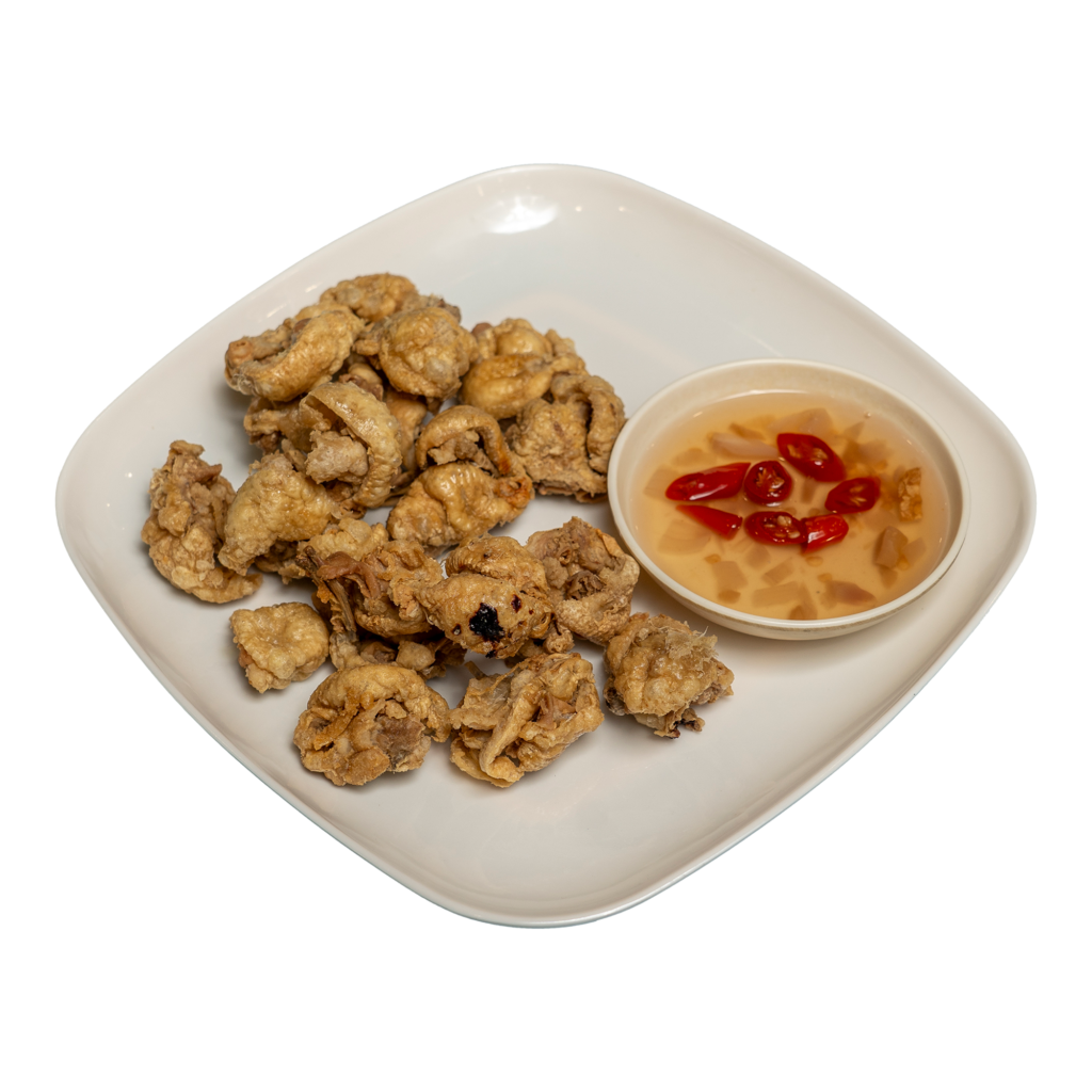 Pieces of cooked chicken skin and a dip on a white plate.